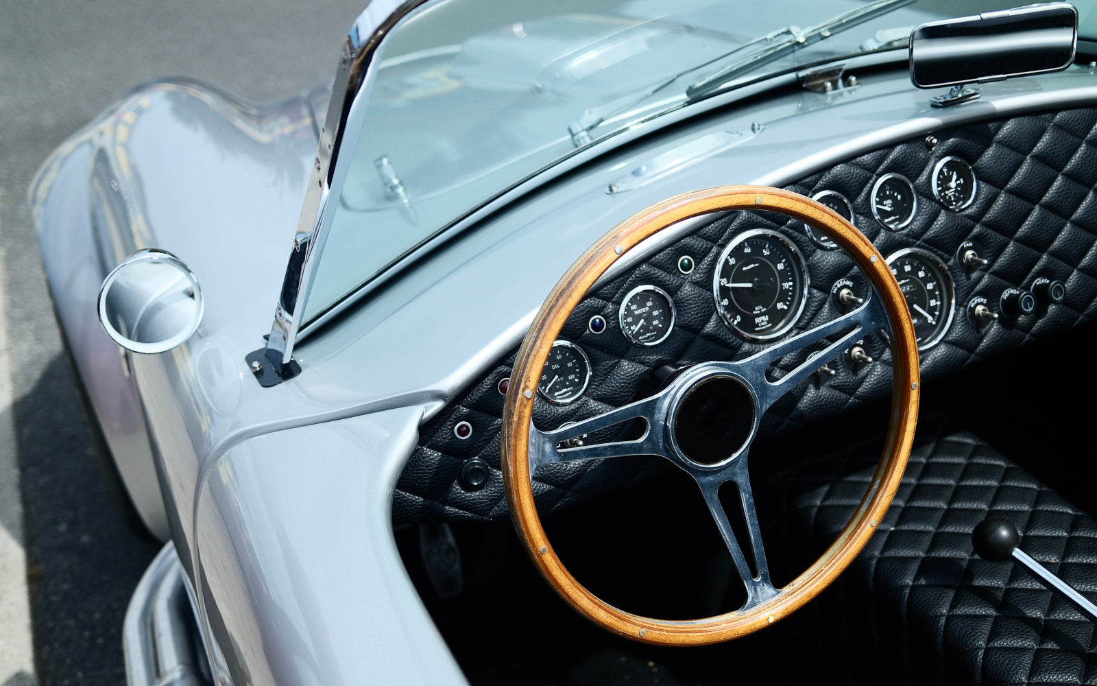 Close up of a vintage sports car interior with a wooden steering wheel and analogue dials, an object operated by hand and read with attention. Baroque Whisky Australian Single Malt.