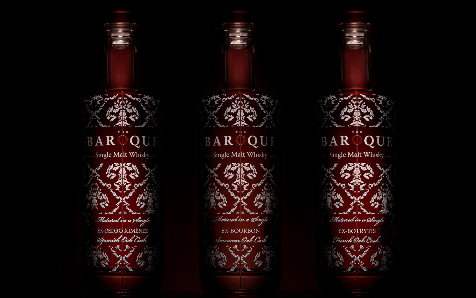 Three Baroque bottles on a red background, finite releases that embody the value of restraint. Baroque Whisky Australian Single Malt.