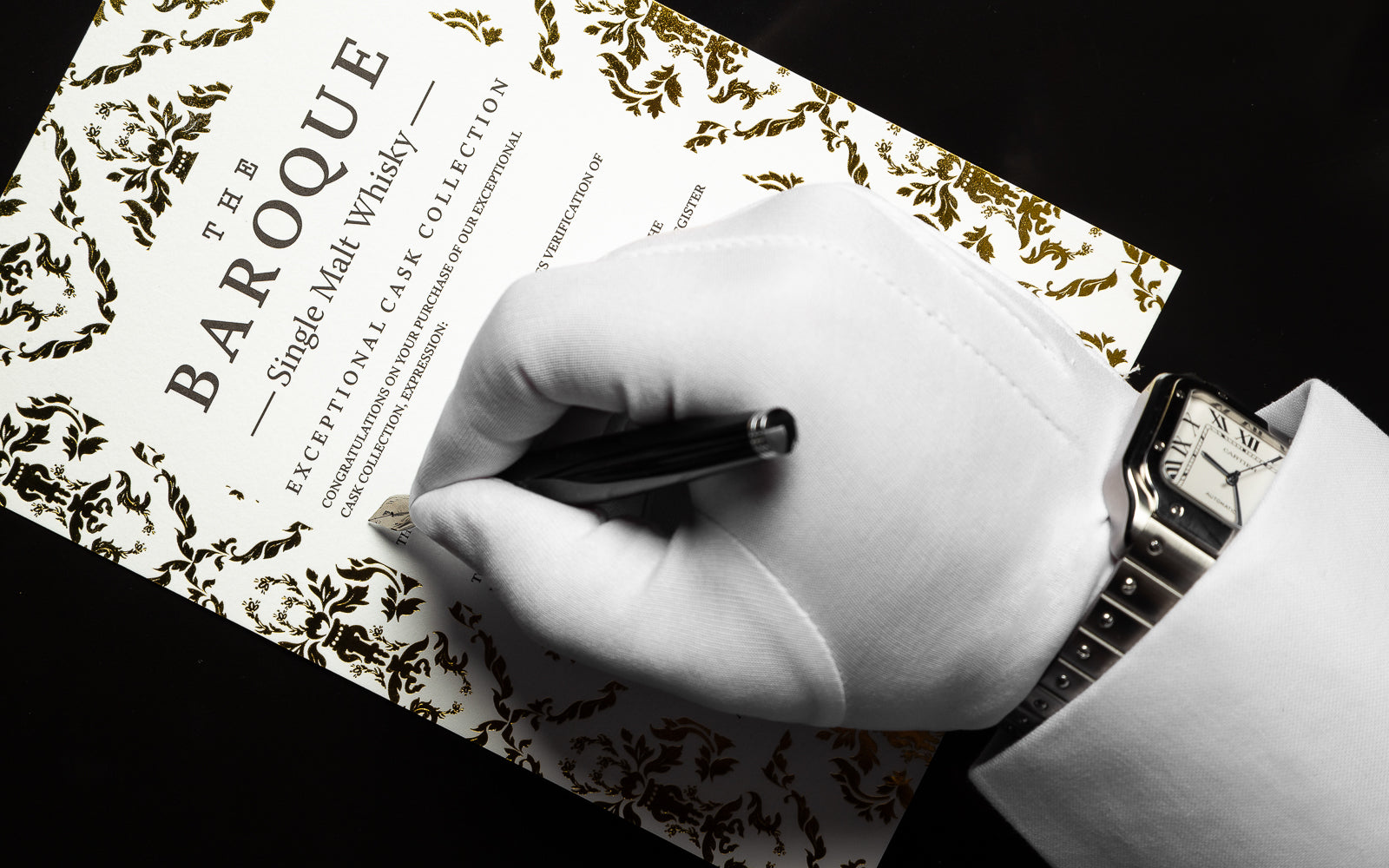 A gloved hand wearing a fine watch signs a Baroque Exceptional Cask Collection allocation certificate.