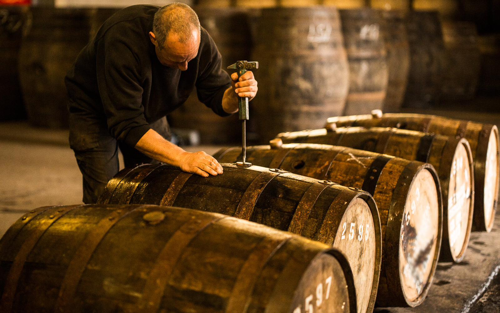 A cooper working on oak barrels in a distillery, tradition refined without stagnation. Baroque Whisky Australian Single Malt.