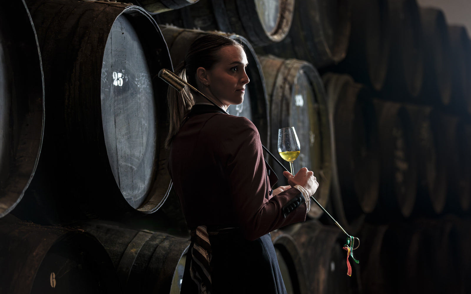 A figure in a cellar holding a glass, the human judgment behind maturation. Baroque Whisky Australian Single Malt.